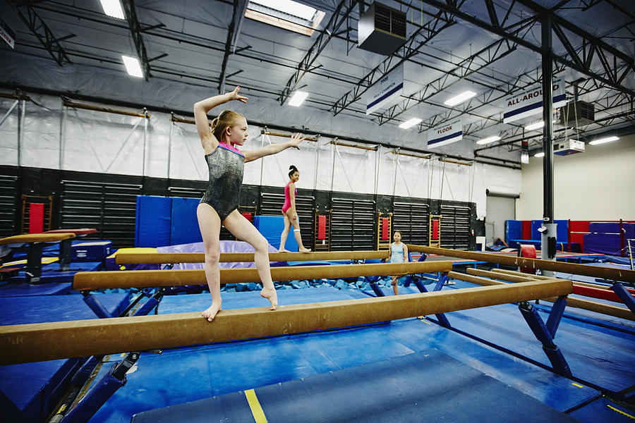 Female gymnast practicing balance beam routine Photograph by Thomas Barwick