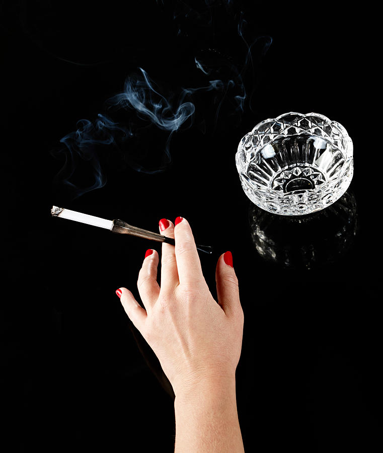 Female hand with cigarette in holder and ashtray Photograph by Image Source