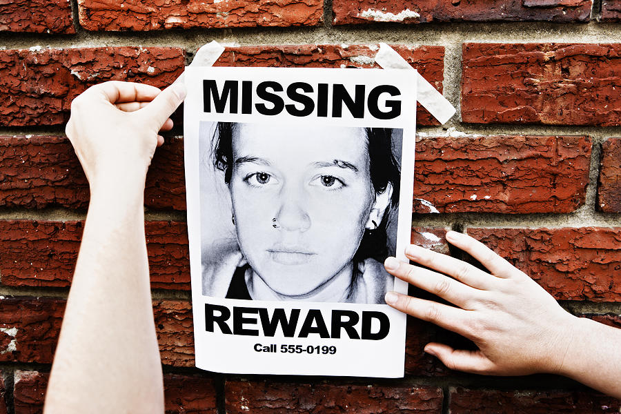 Female hands attach "Missing" poster of teenage girl to wall Photograph by RapidEye