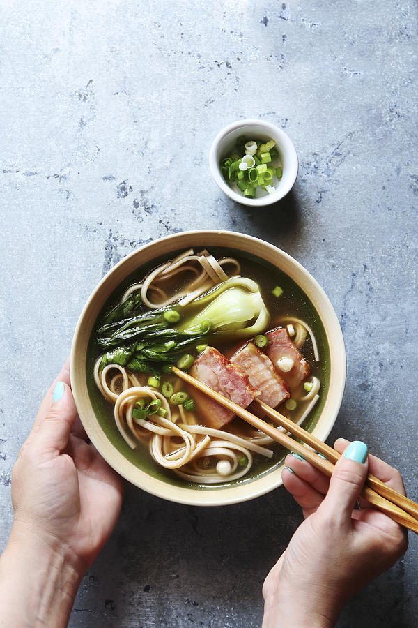 Female hands holding a bowl of pork belly udon noodle soup.Top view Photograph by The Picture Pantry