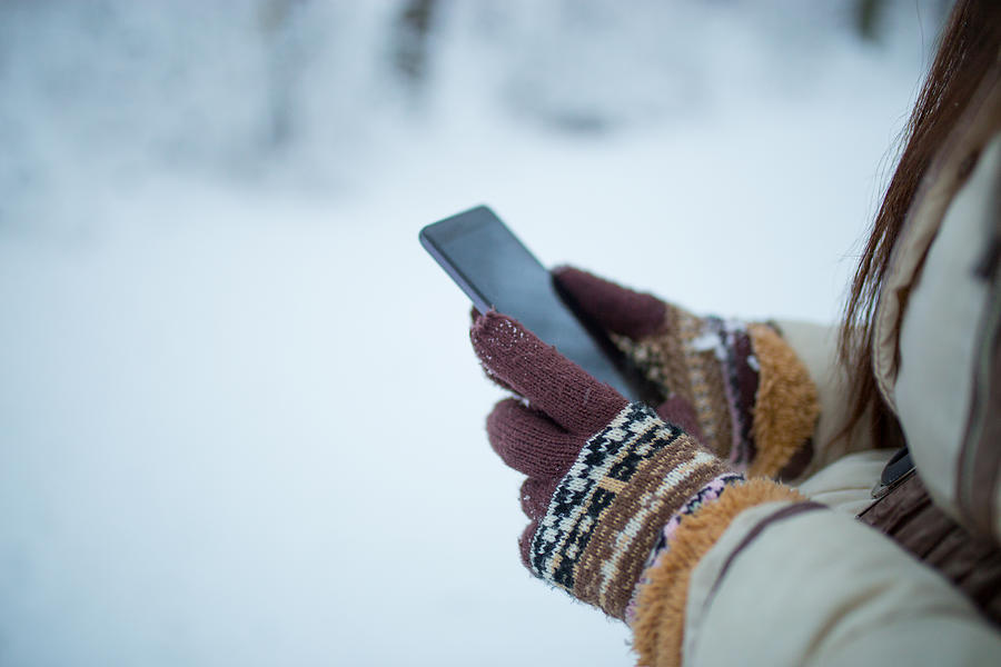 Female hands holding a cellphone outdoors in the snow Photograph by Milan_Jovic