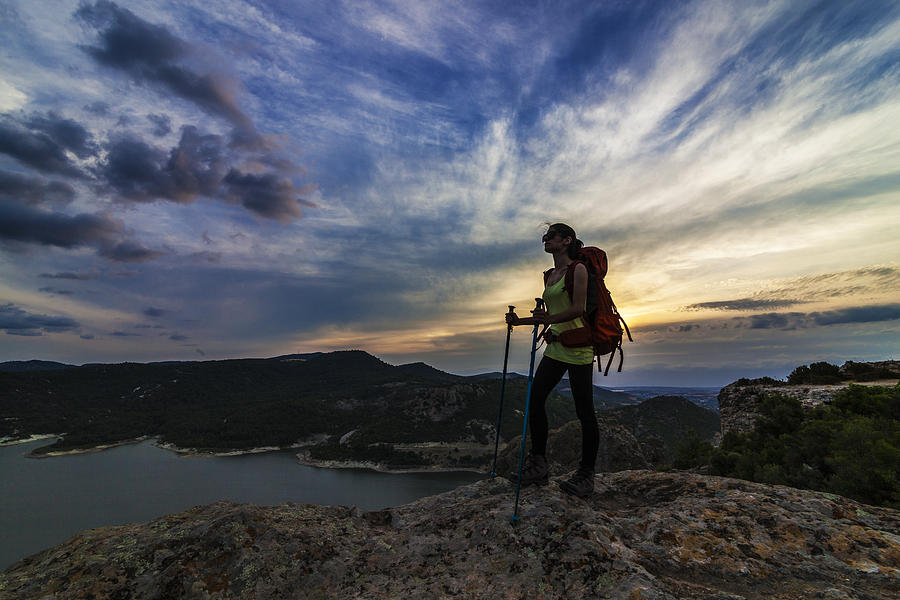 Female hiker climbing to mountain peak at sunset Photograph by Guvendemir