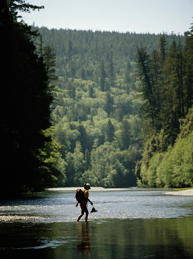 Female hiker crossing river, side view Photograph by Steve Casimiro