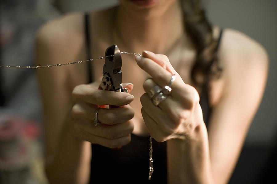 Female jeweller cutting chain with pincers, close-up Photograph by Nisian Hughes