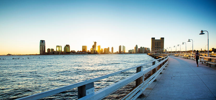 Female jogger on Manhattan pier with Jersey City and sunset Photograph by NicolasMcComber