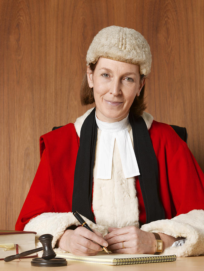 Female judge sitting at desk, smiling, portrait, close-up Photograph by Peter Dazeley