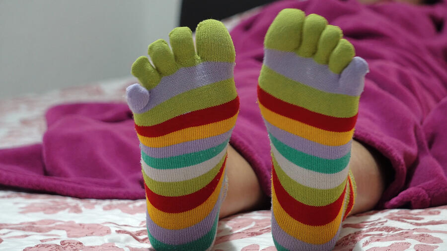 Female legs in socks with toes relaxing in bed Photograph by Zefart