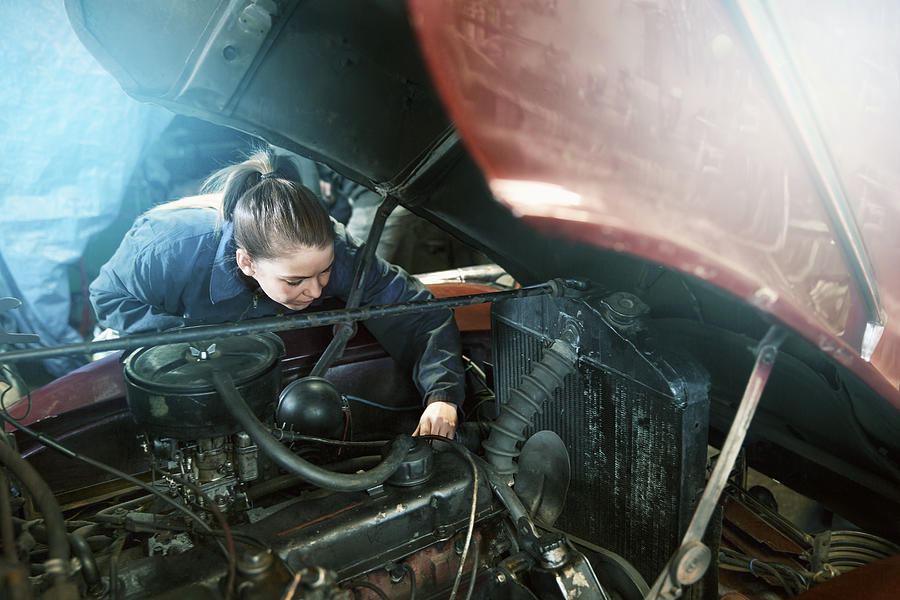 Female motor mechanic working on a car engine. Photograph by Portra