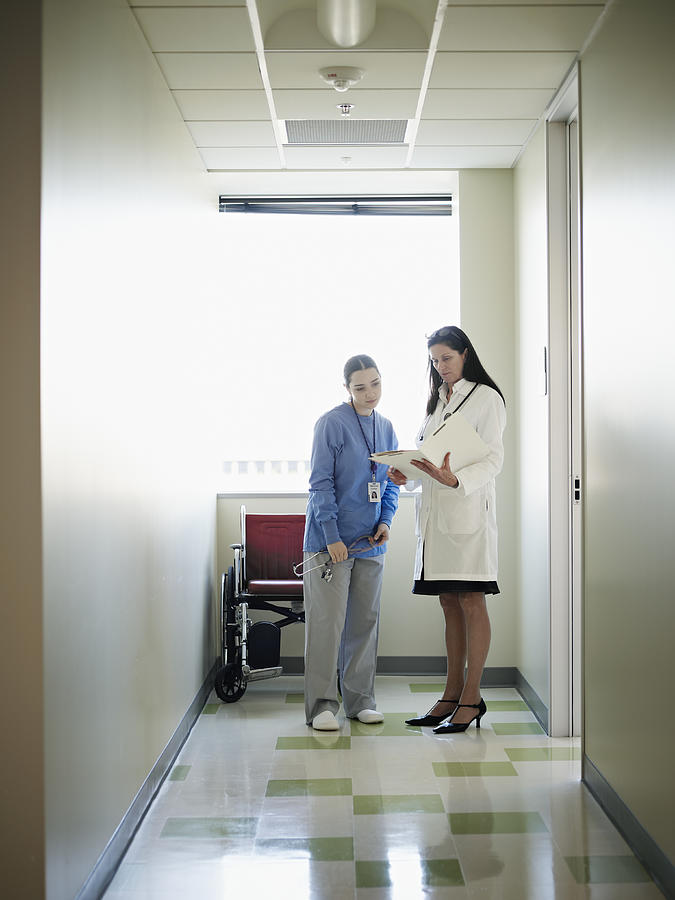 Female nurse and doctor discussing patient chart Photograph by Thomas Barwick