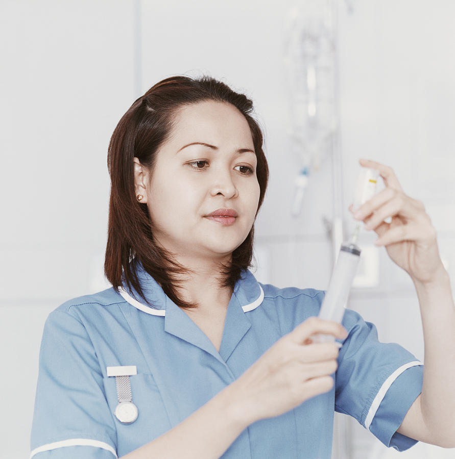 Female Nurse Measures Medicine Into a Syringe Photograph by Janie Airey