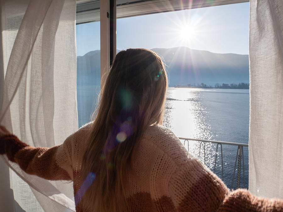 Female opens curtains at sunrise, new beginning new day Photograph by Swissmediavision