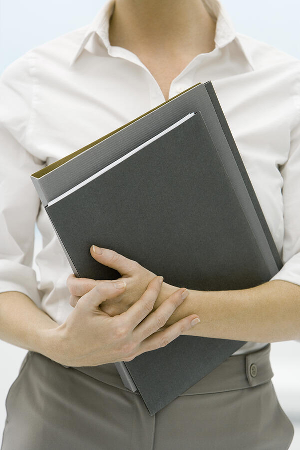 Female professional holding folders, cropped view Photograph by PhotoAlto/Alix Minde