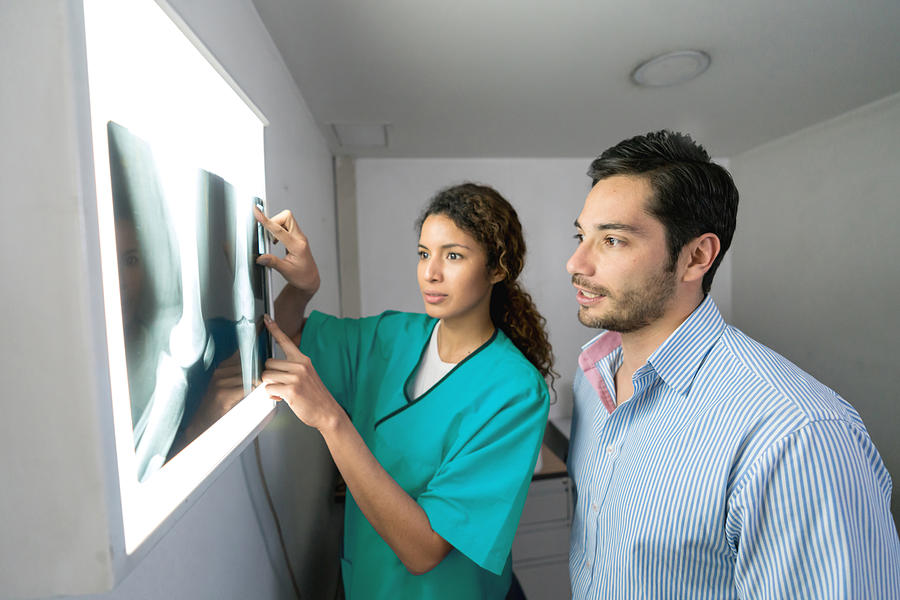 Female radiologist and male orthopedist discussing an x-ray of a patient Photograph by Andresr