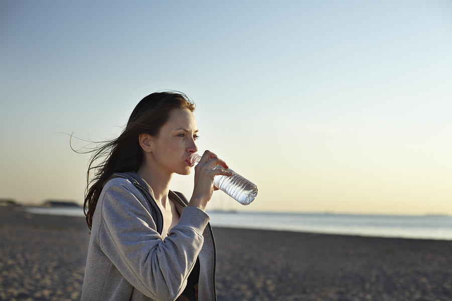 Female runner drinking water at the beach Photograph by Klaus Vedfelt