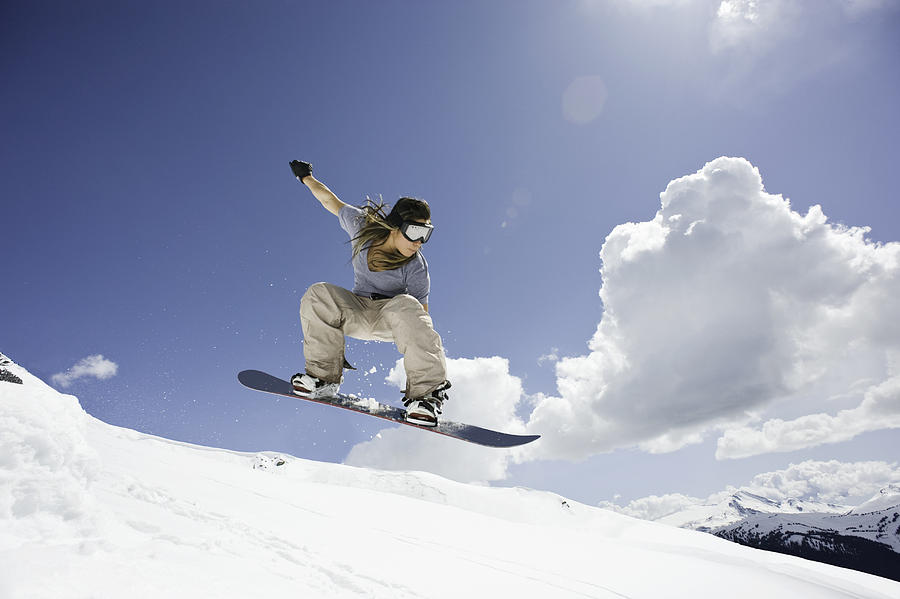 Female Snowboarder Jumping Through Air Photograph by Darryl Leniuk
