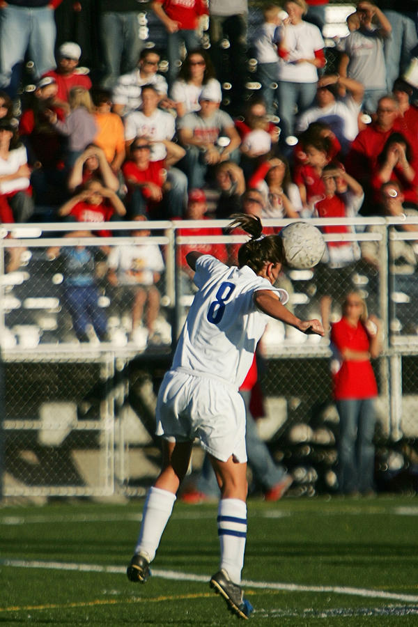 Female Soccer Player Heads Ball with Spectators and Copy Space Photograph by Strickke
