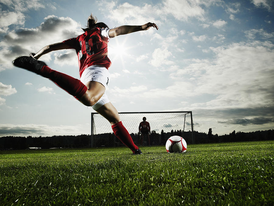 Female soccer player kicking ball toward goal Photograph by Thomas Barwick