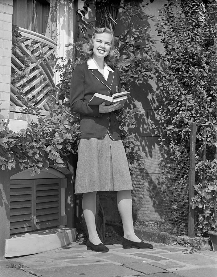 Female student holding book in back yard, portrait Photograph by George Marks