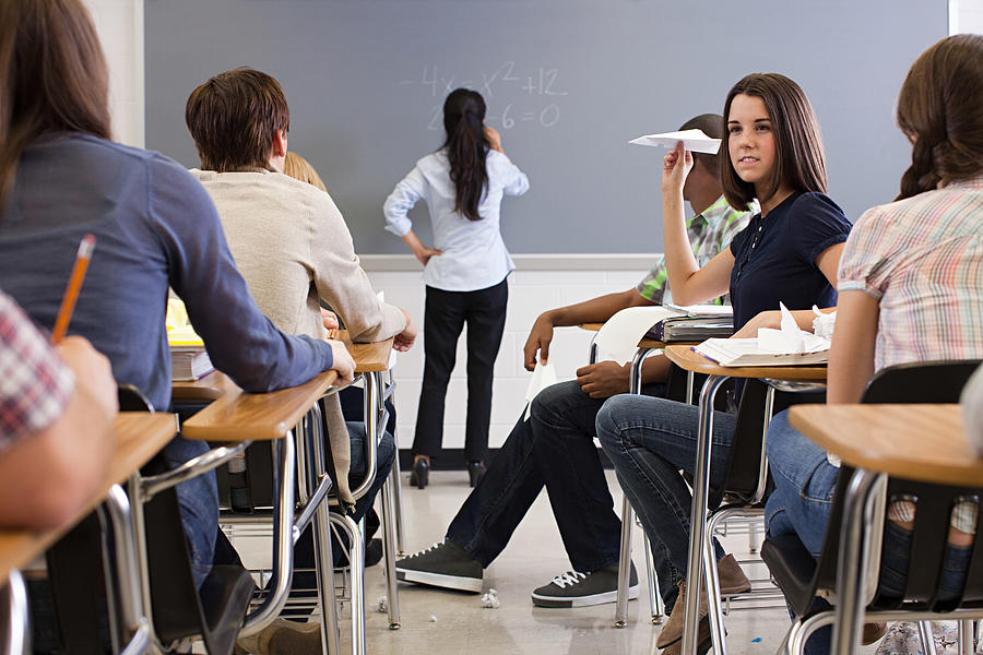 Female student with paper aeroplane in classroom Photograph by Image Source