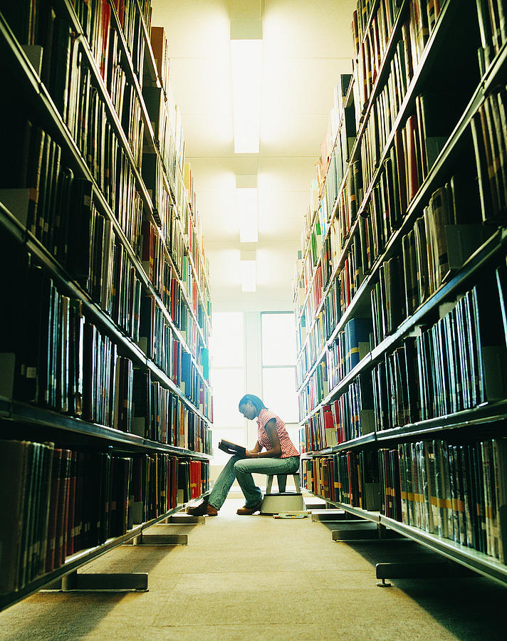 Female University Student Reading a Book in a Library Photograph by Digital Vision.