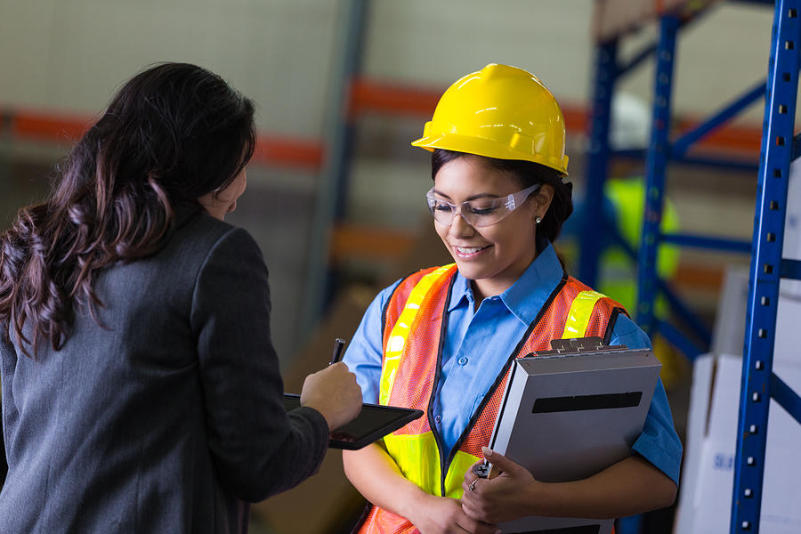 Female warehouse worker and supervisor checking shipping order Photograph by SDI Productions