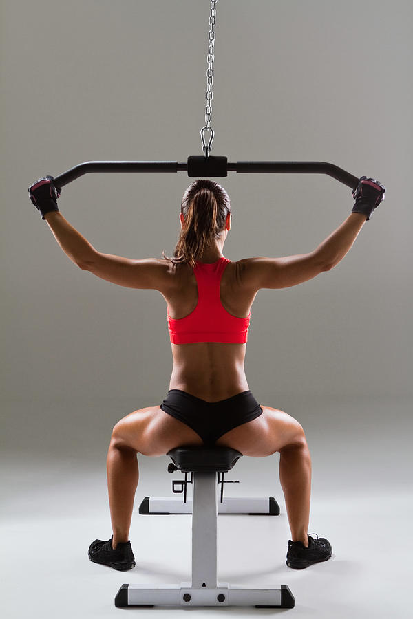 Female weightlifter using weight machine Photograph by Image Source