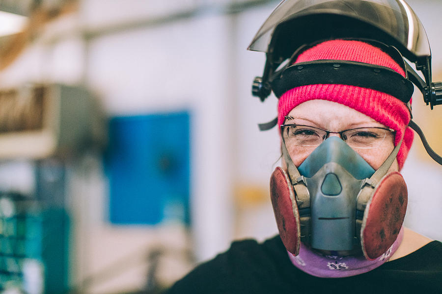 Female worker wearing a mask and helmet. Smiling at camera Photograph by MmeEmil
