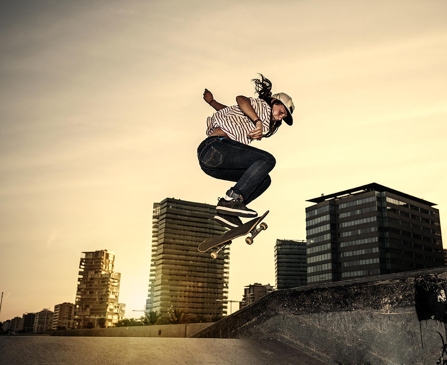 Female young skateboarder jumping in skatepark in the city Photograph by Aluxum