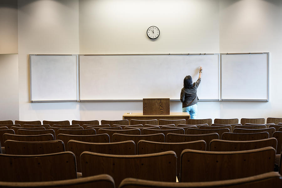 Filipino professor writing on whiteboard in empty lecture hall Photograph by Hill Street Studios