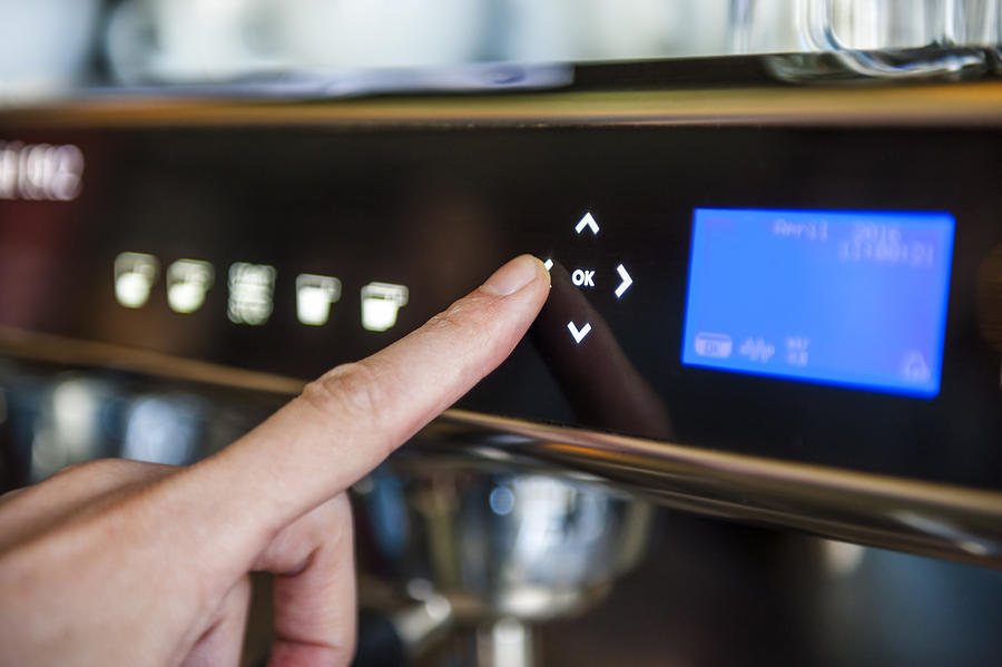 Finger pushing digital button on coffee machine Photograph by Westend61