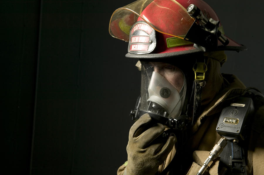 Fire fighter standing in uniform wearing face mask Photograph by Photodisc