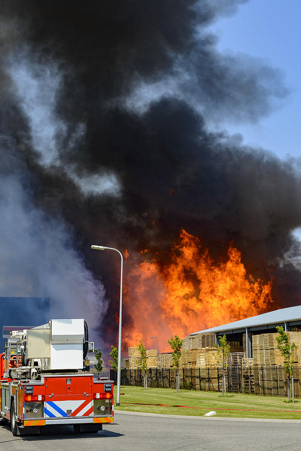 Fire truck in front of a large fire in a factory in an industrial area Photograph by Sjo