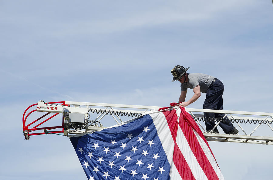 Fireman hanging a flag in a Patriotic Parade Photograph by Bauhaus1000