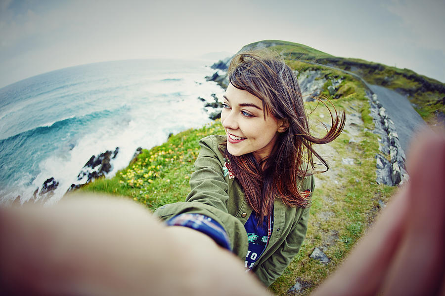 Fish-eye lens of woman taking selfie on mountain by sea Photograph by Neustockimages