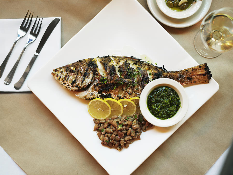 Fish grilled with salsa verde and cranberry beans, close-up Photograph by Thomas Barwick