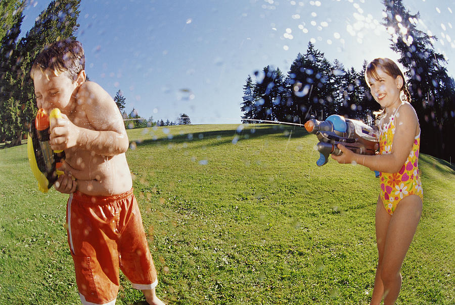 Fisheye Lens Shot of a Young Girl Spraying a Boy with Water from a Water Pistol Photograph by Darryl Leniuk