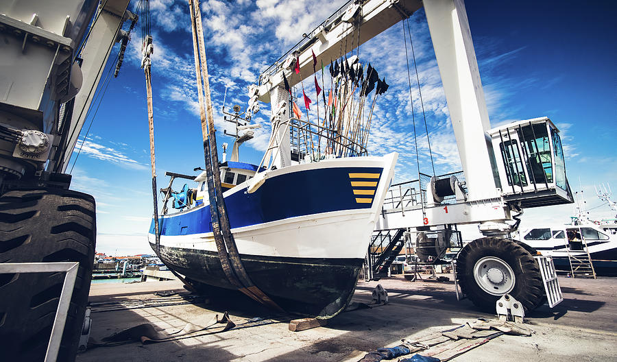 Fishing boat lifted by a boat lift Photograph by Jean-Luc Farges