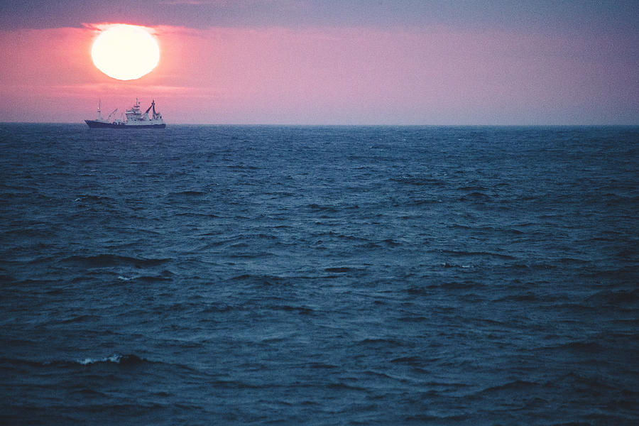Fishing boat sailing rough sea at dawn Photograph by Piola666