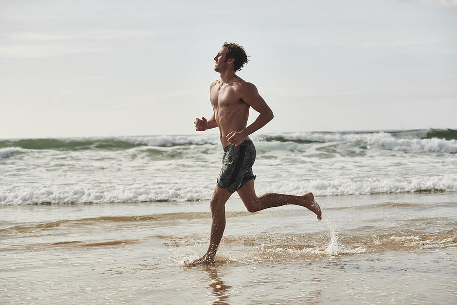 Fit male running on beach Photograph by Matthew Leete