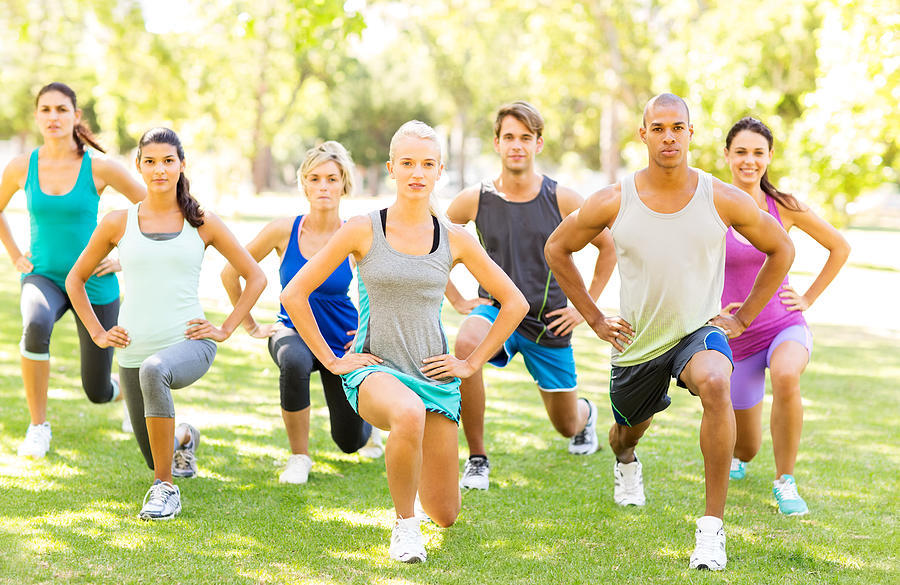 Fitness Class Performing Stretching Exercise In Park Photograph by Neustockimages