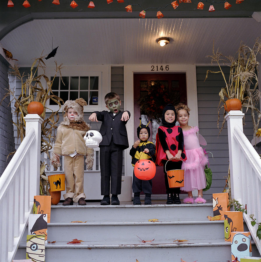 Five children standing on porch, wearing Halloween costumes, portrait Photograph by Ryan McVay