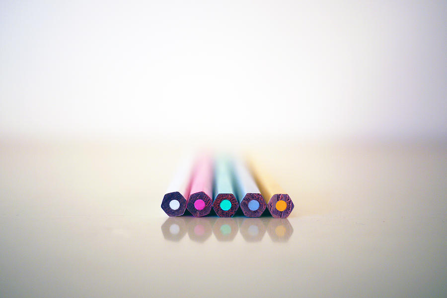 Five soft colored pencils on white, reflected on luminous surface Photograph by Rosmarie Wirz