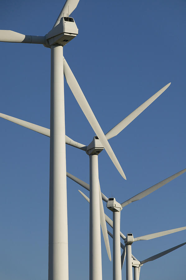 Five Wind Turbines in a Row Against a Blue Sky Photograph by Digital Vision.