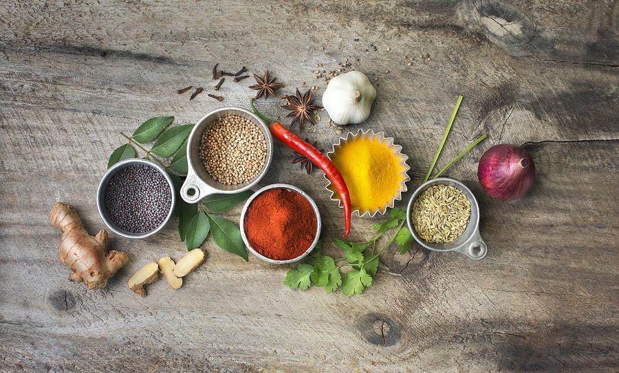 Flat lay overhead view herb and spices on rustic wooden background. Photograph by Twomeows