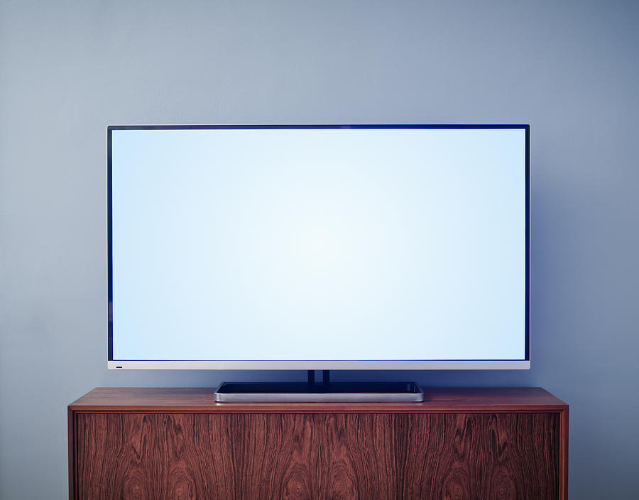 Flat screen TV on cabinet Photograph by Jorg Greuel