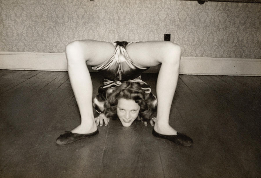 Flexible Woman on the Living Room Floor With Her Legs Over Her Head Photograph by Digital Vision.