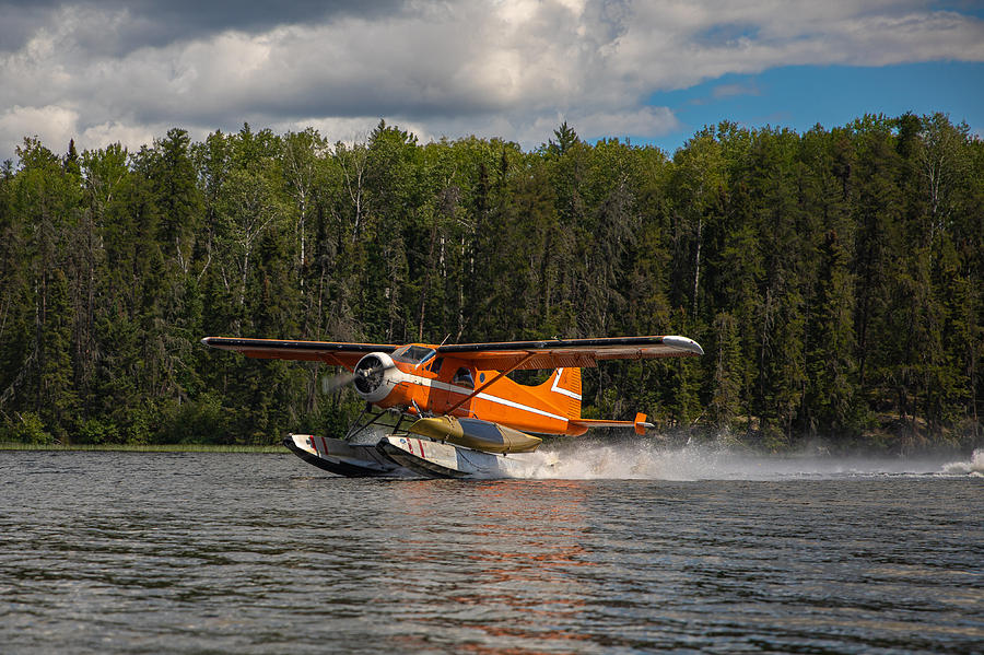 Float plane taking off from a lake with a canoe tied on. Photograph by Harlan Schwartz