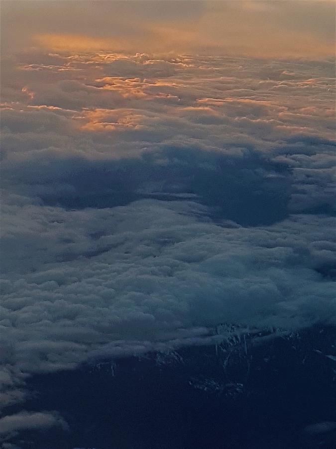 Flying above the clouds and mountains at sunset Photograph by James Cousineau