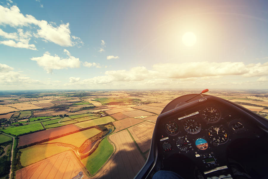 Flying glider aircraft over farmland with sun in sky Photograph by Sean Gladwell