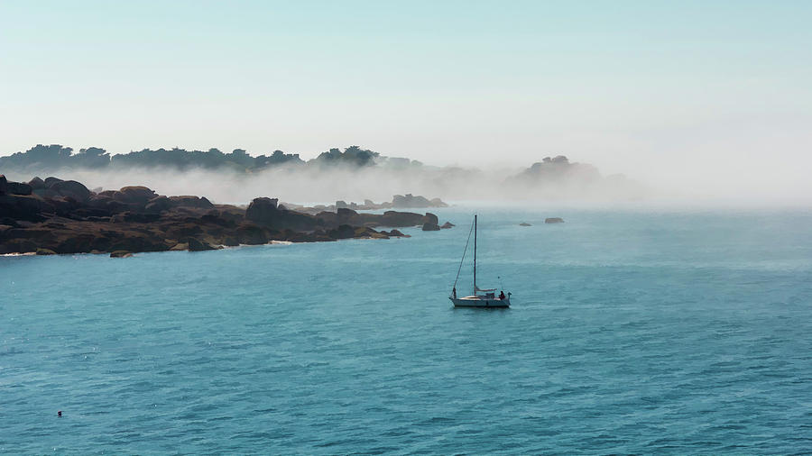 Boat going fishing on the rocky coast of French Brittany on a